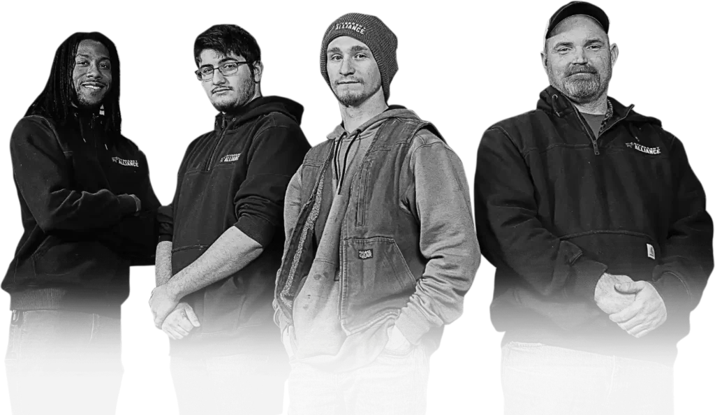Four individuals stand side by side, wearing dark hoodies, against a black background. Their arms are crossed or relaxed at their sides.